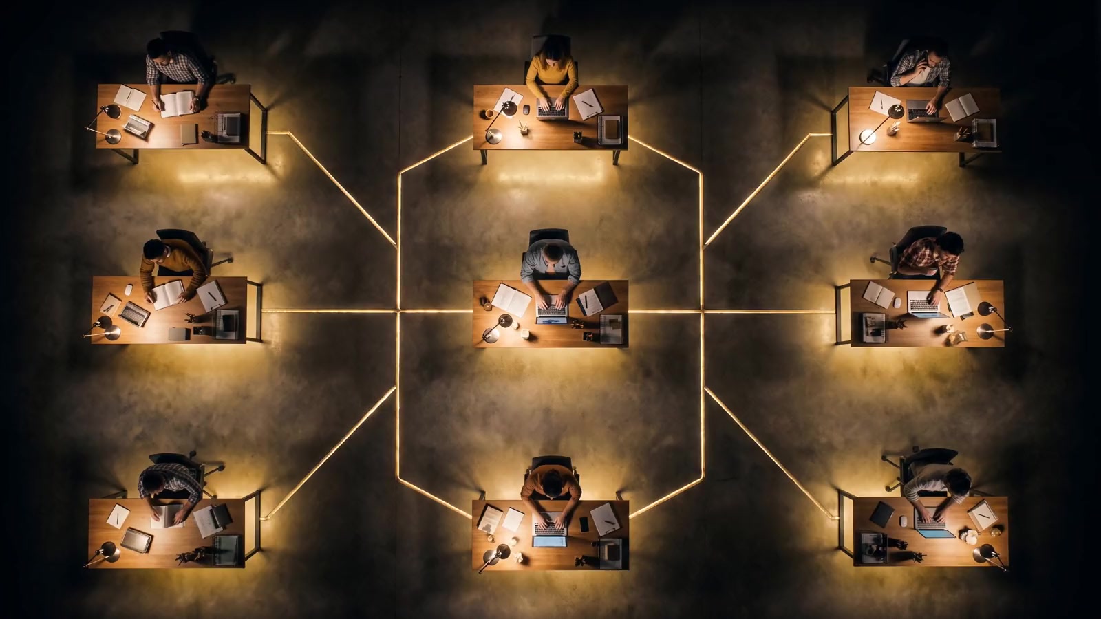 An office floor from above, a golden thread of light rising from every desk